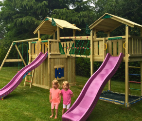 Aire de jeux en bois avec deux toboggans, filet d'escalade, pont en filet et balançoires dans un jardin